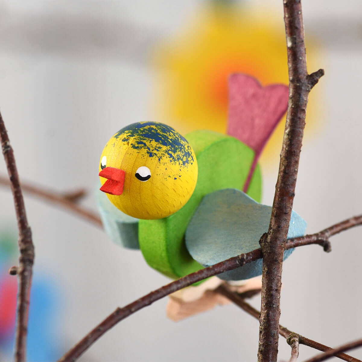 Vogel mit Klammer hellgrün mit blauen Flügeln